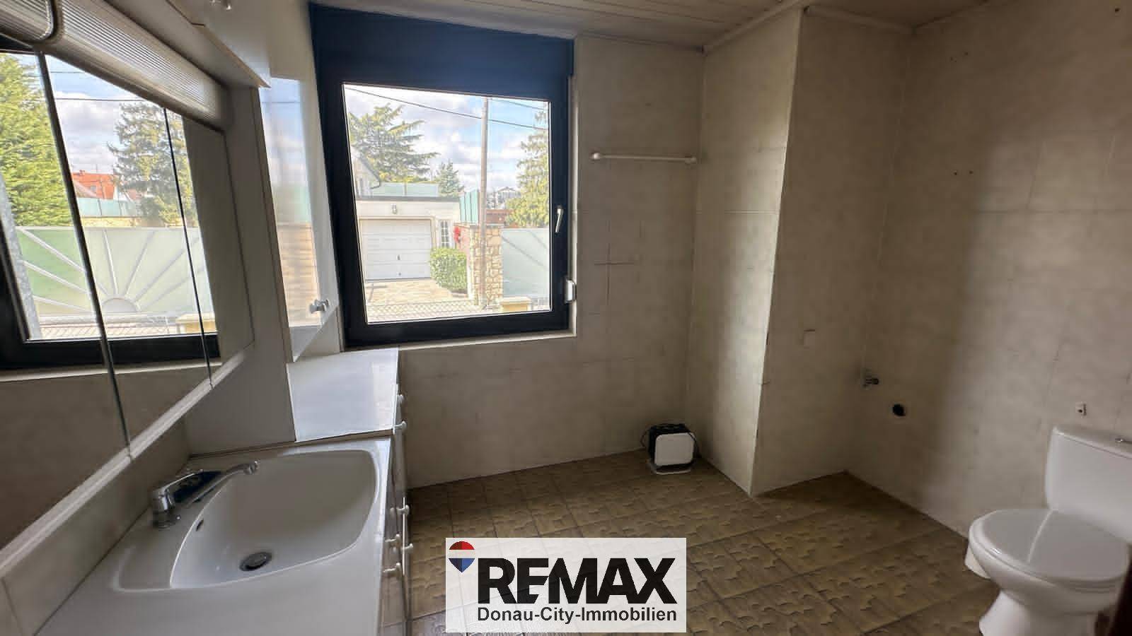 Badezimmer mit WC, Waschbecken und Fenster mit Blick auf die Einfahrt.