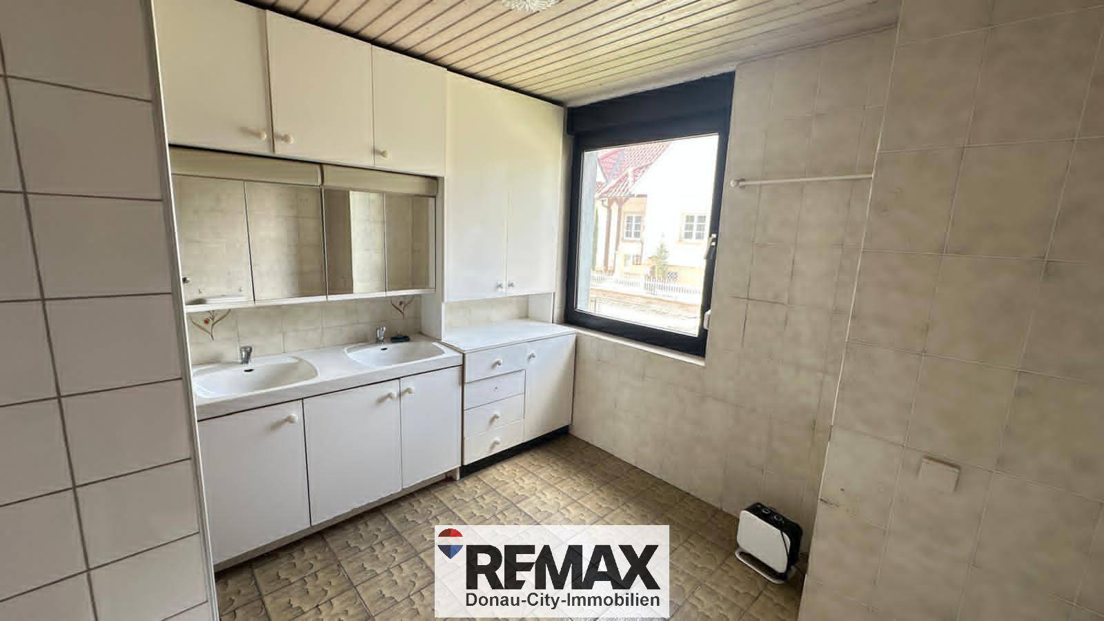Badezimmer mit Doppelwaschbecken, Spiegelschrank und Fliesen an Wänden und Boden.