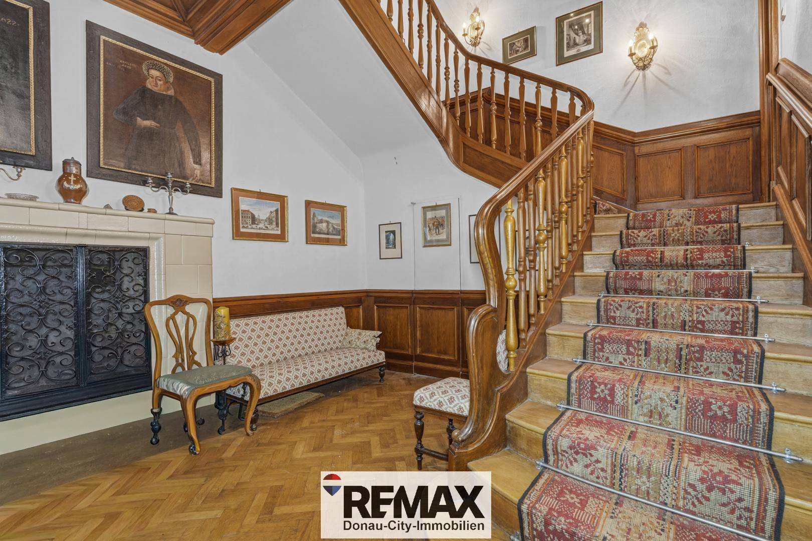 Repräsentativer Eingangsbereich mit einer eleganten Holztreppe, Parkettboden und Kamin.