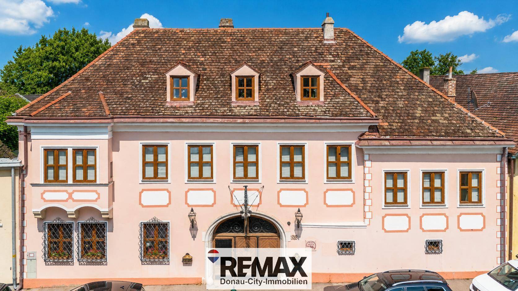 Historische Fassade eines Gebäudes mit mehreren Fenstern und einem großen Eingangstor.