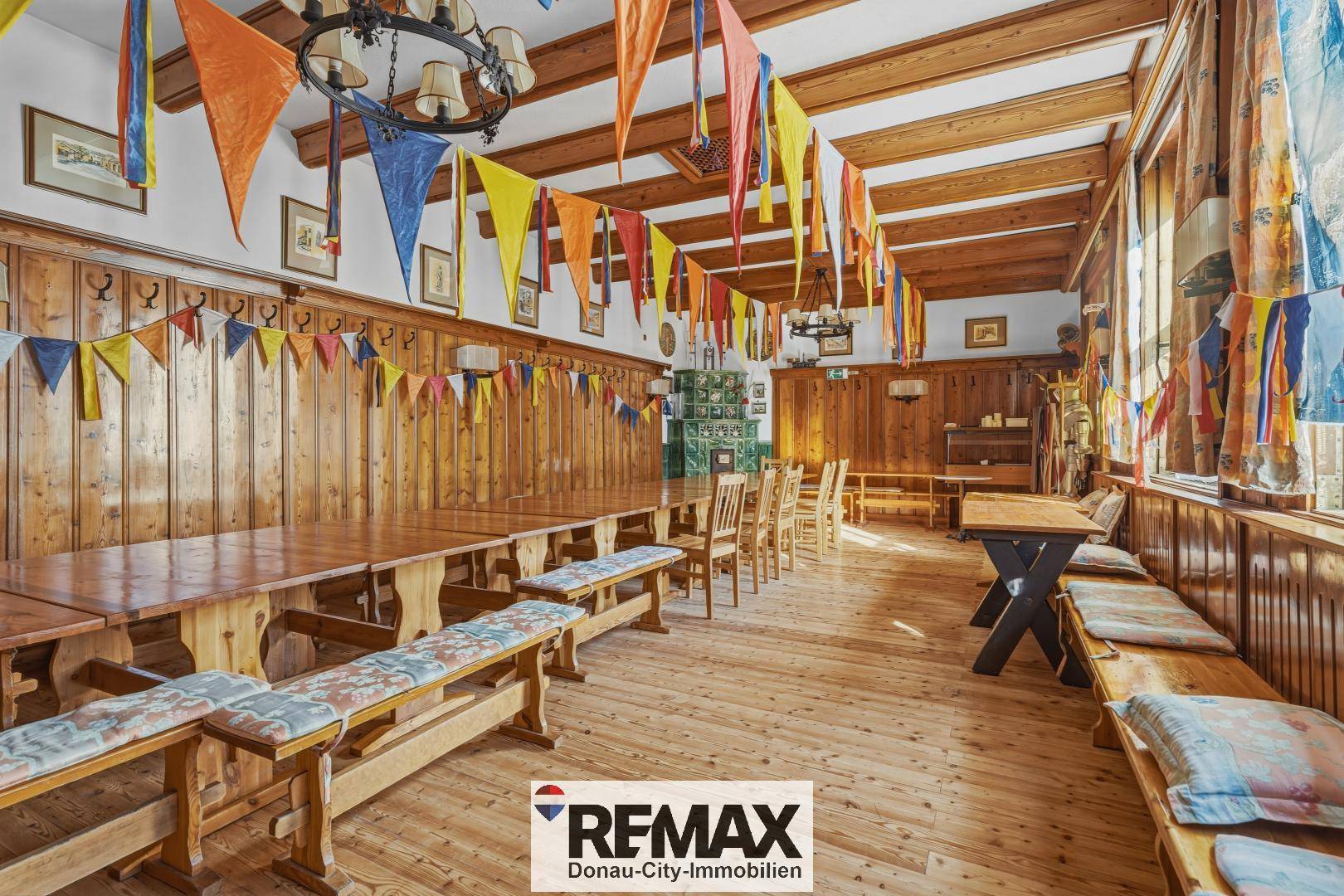 Großer Saal mit Holzböden, Holzwänden und langen Tischen für Veranstaltungen.