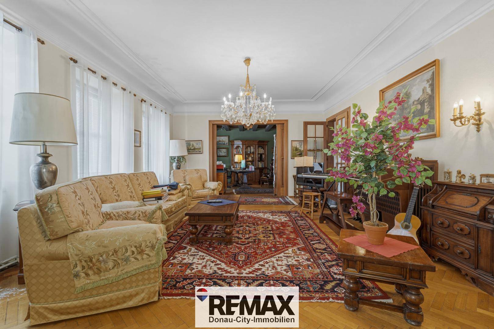 Geräumiges Wohnzimmer mit klassischer Einrichtung, Kronleuchter und Parkettboden.