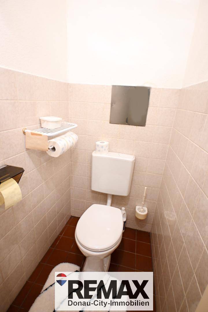 Separates WC mit hellen Fliesen und Toilette, funktional und sauber.