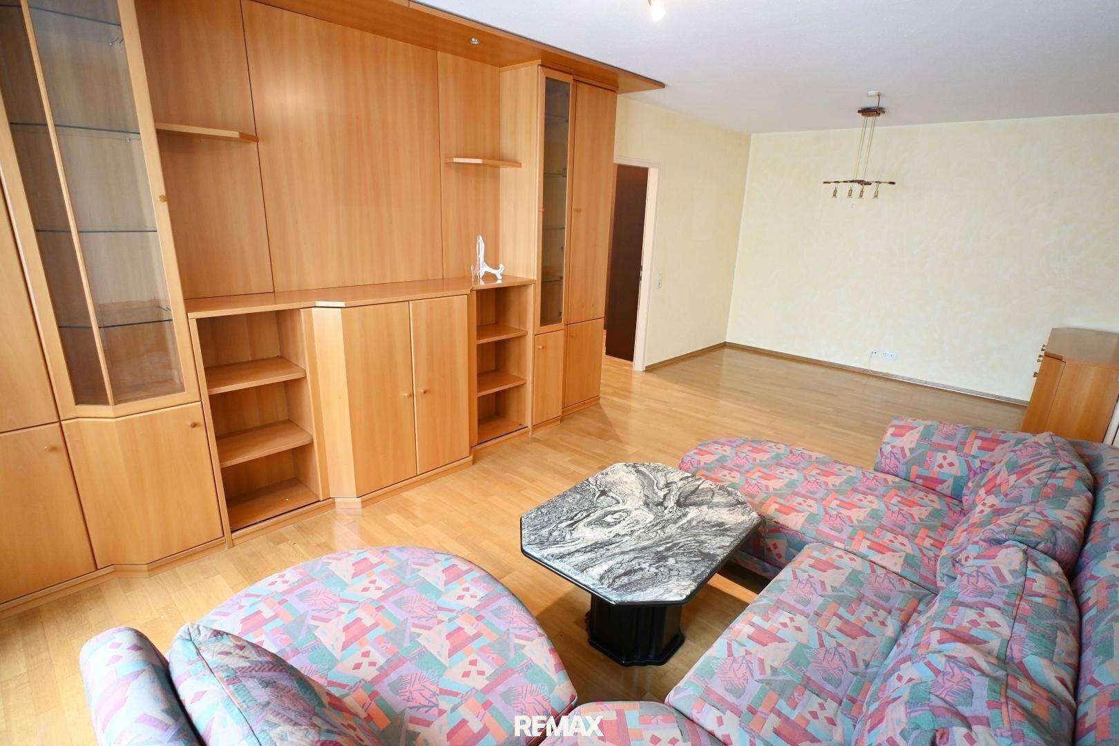 Wohnzimmer mit großer Holzschrankwand, Ecksofa und Marmor-Couchtisch, klassisch eingerichtet.