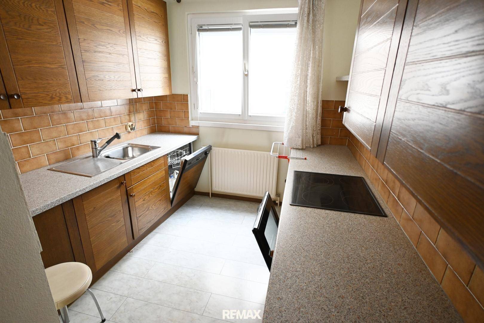 Funktionale Küche mit Holzschränken, Fliesenrückwand und Spülmaschine, hell und praktisch.