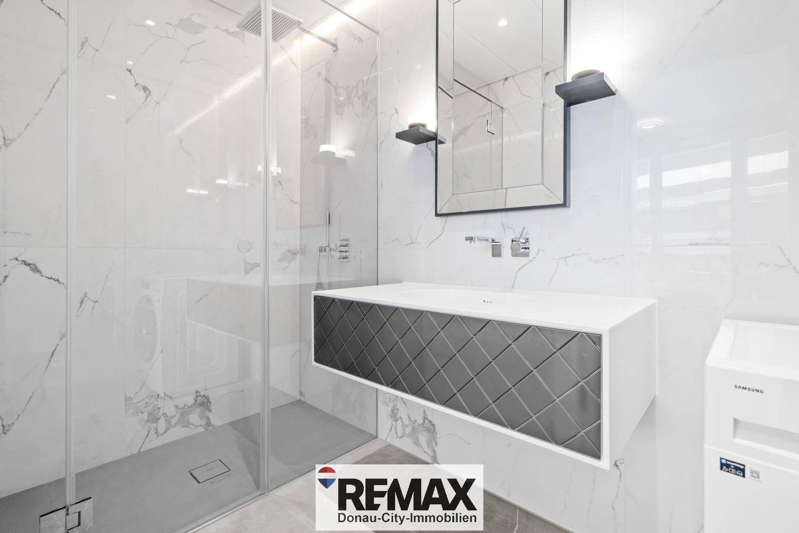 Elegantes Badezimmer mit Marmorfliesen, begehbarer Dusche und modernem Waschtisch.