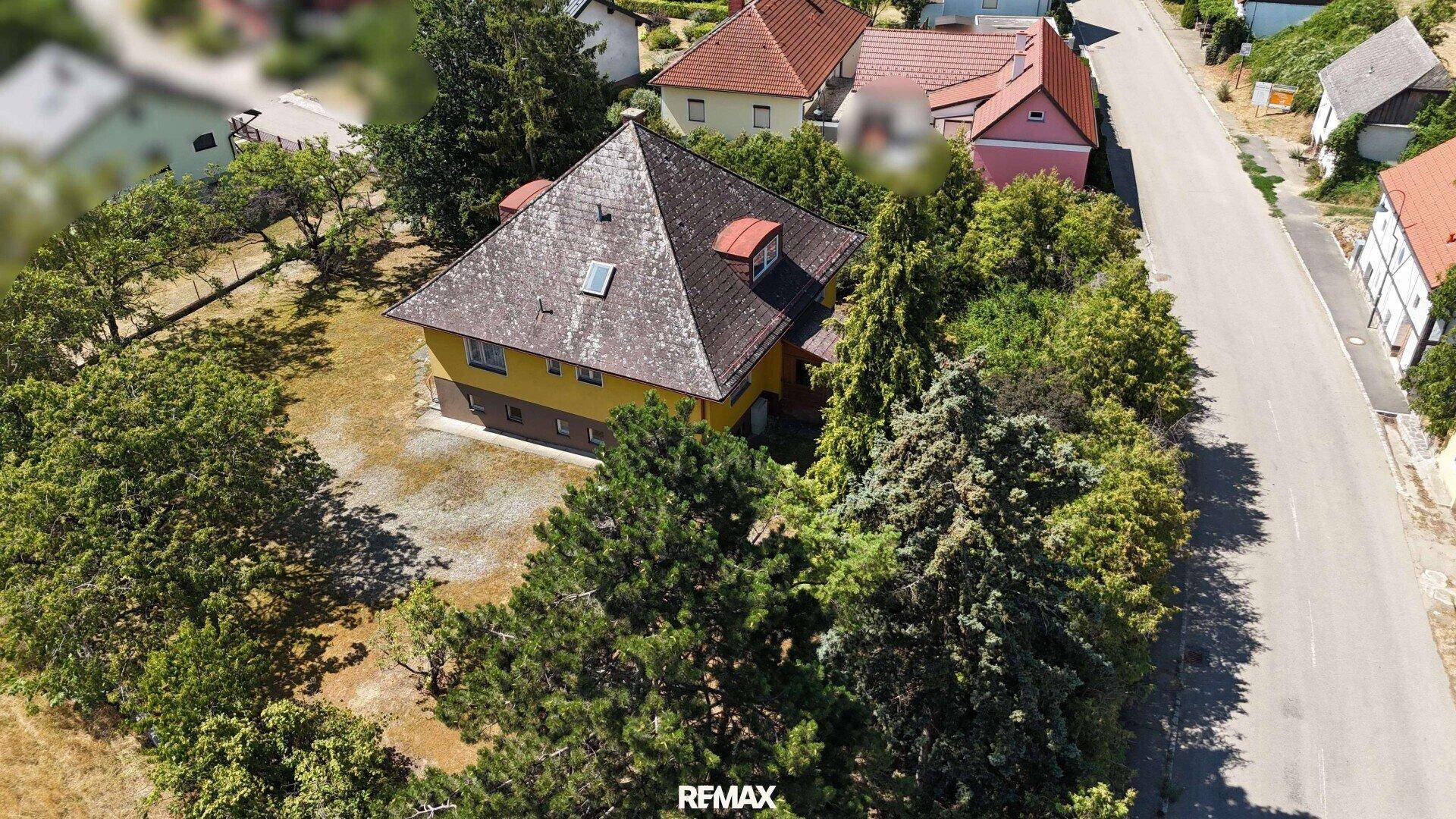 Luftaufnahme des Hauses mit umliegender Natur und angrenzender Straße.