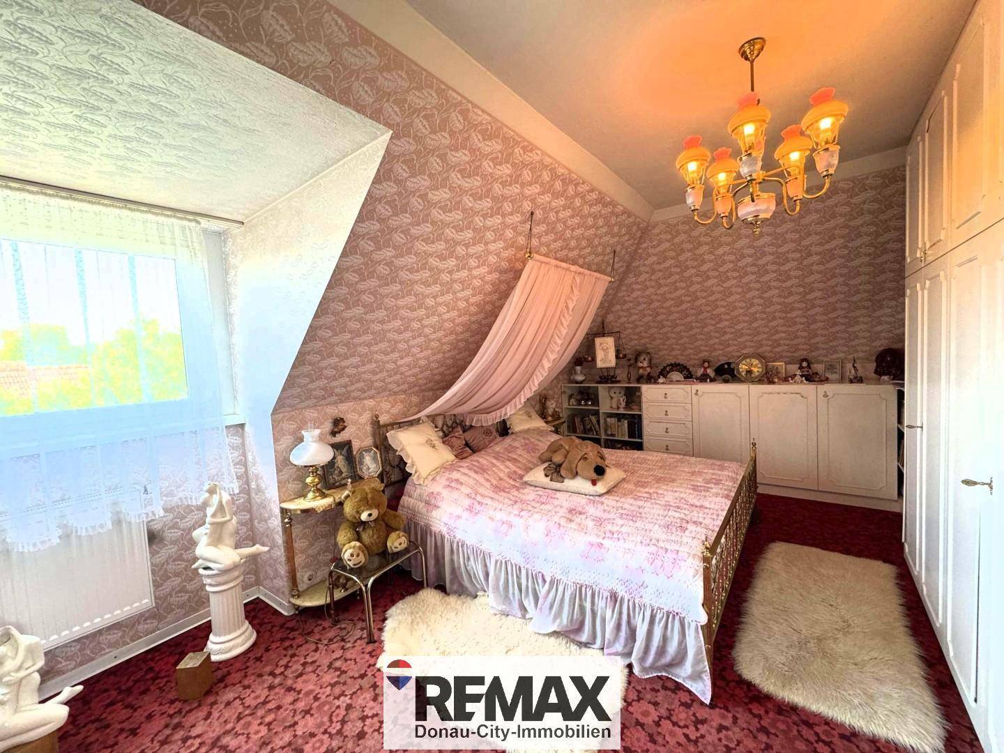 Schlafzimmer im Dachgeschoss mit schräger Decke, gemustertem Teppich und traditionellem Bett.