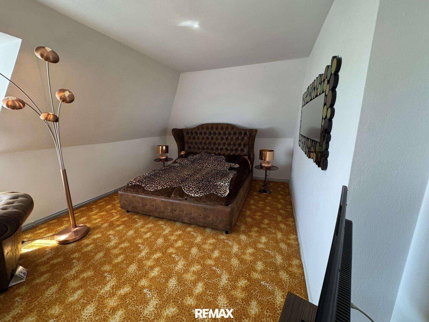 Schlafzimmer im Dachgeschoss mit Teppichboden, Doppelbett und Dachschräge.