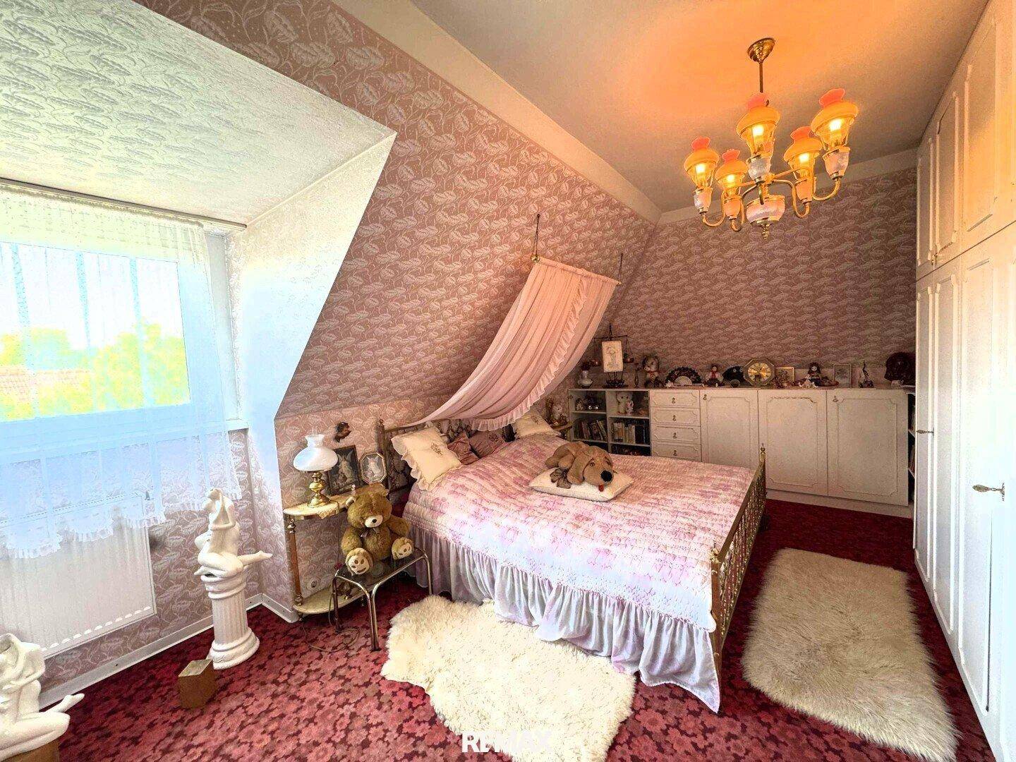 Gemütliches Schlafzimmer im Dachgeschoss mit Teppichboden, Himmelbett und Dachschräge.