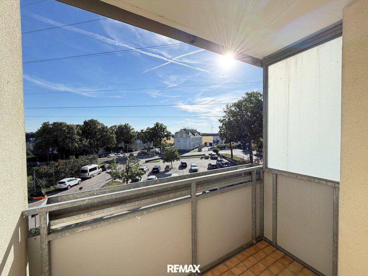 Heller Balkon mit Metallgeländer und Blick auf die Straße und umliegende Gebäude.