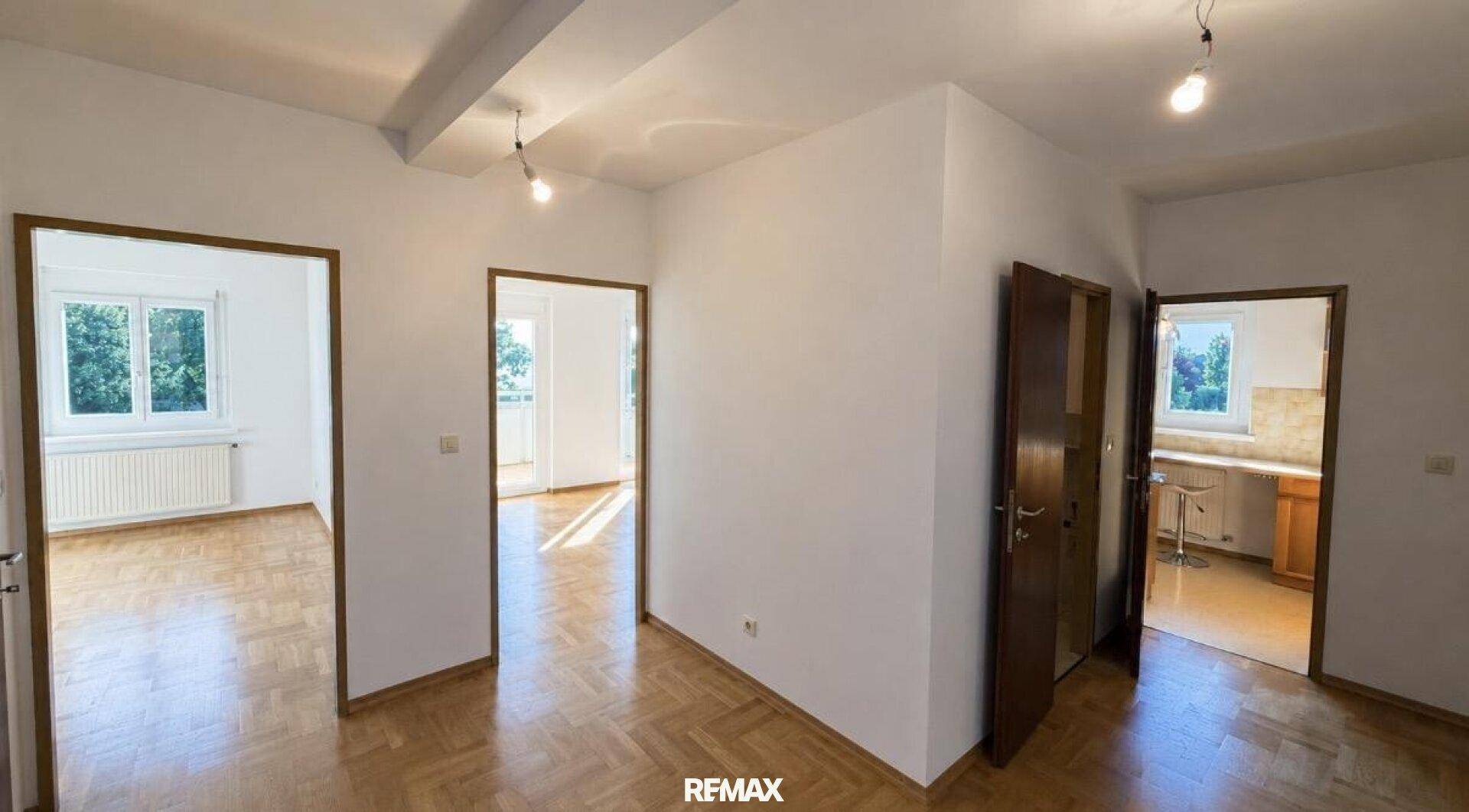 Heller Flur mit Fischgrätparkettboden und Zugängen zu verschiedenen Zimmern der Wohnung.