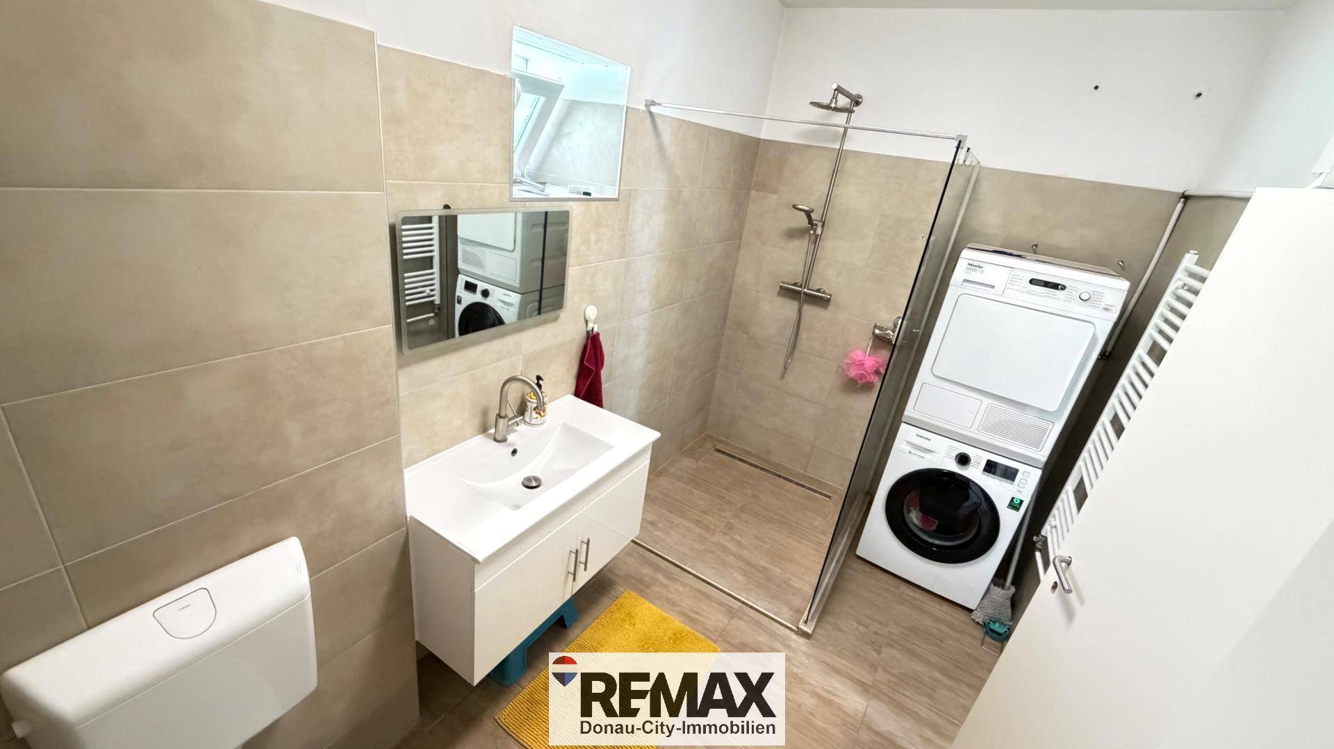 Helles Badezimmer mit Dusche, Waschbecken, Toilette und einem Dachfenster für natürliches Licht.