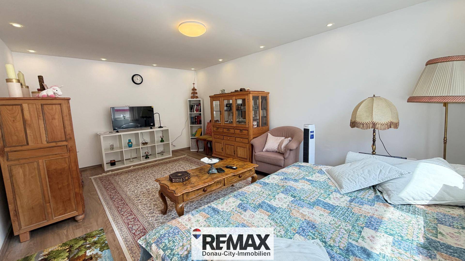 Geräumiger Wohnbereich mit Bett, traditionellen Holzmöbeln und einem Fernseher.