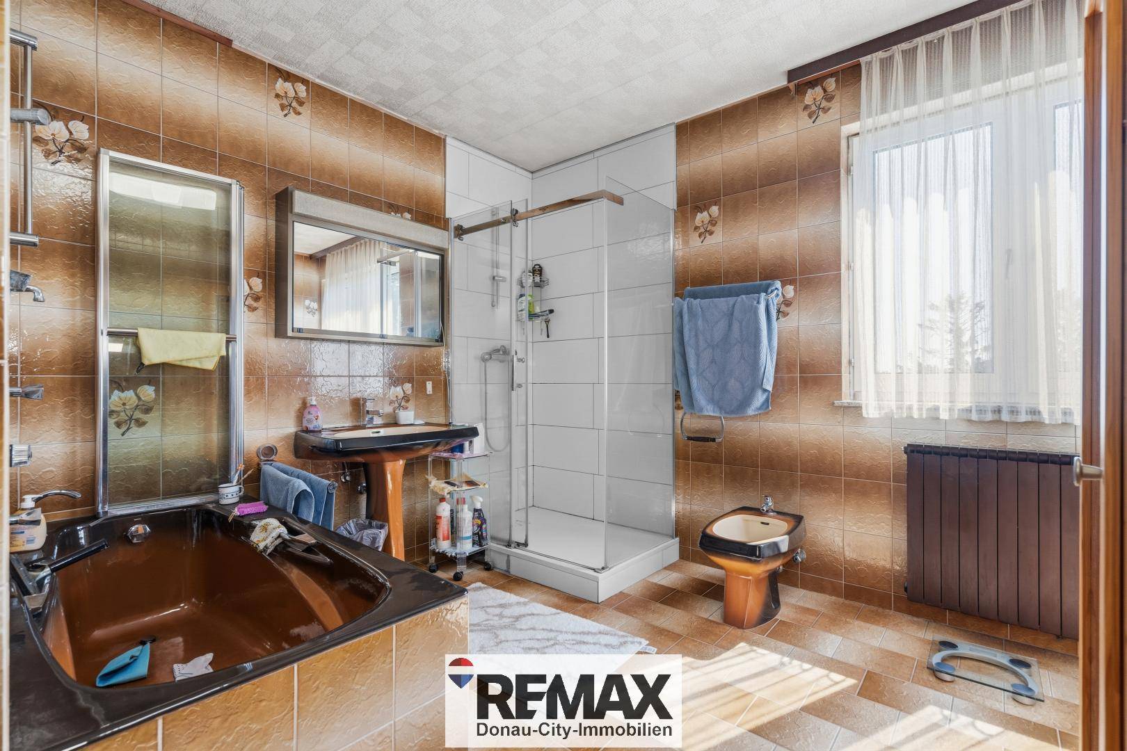 Badezimmer mit braunen Fliesen, Badewanne, Duschkabine, Waschbecken und Bidet.
