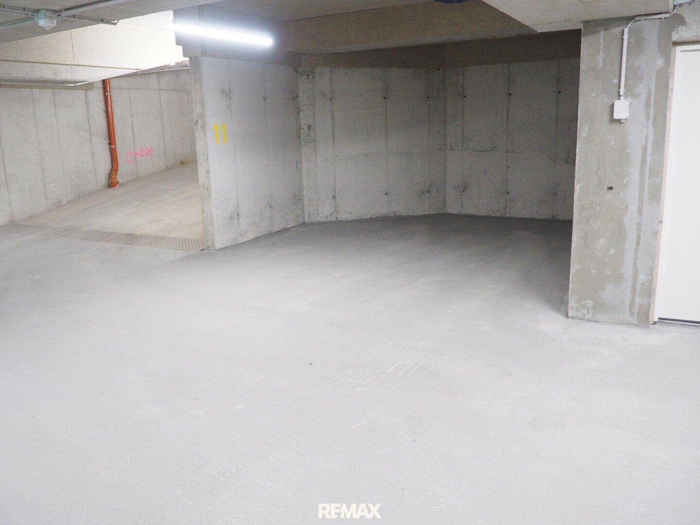Leerer Raum im Untergeschoss mit unverputzten Betonwänden und einem glatten Betonboden.