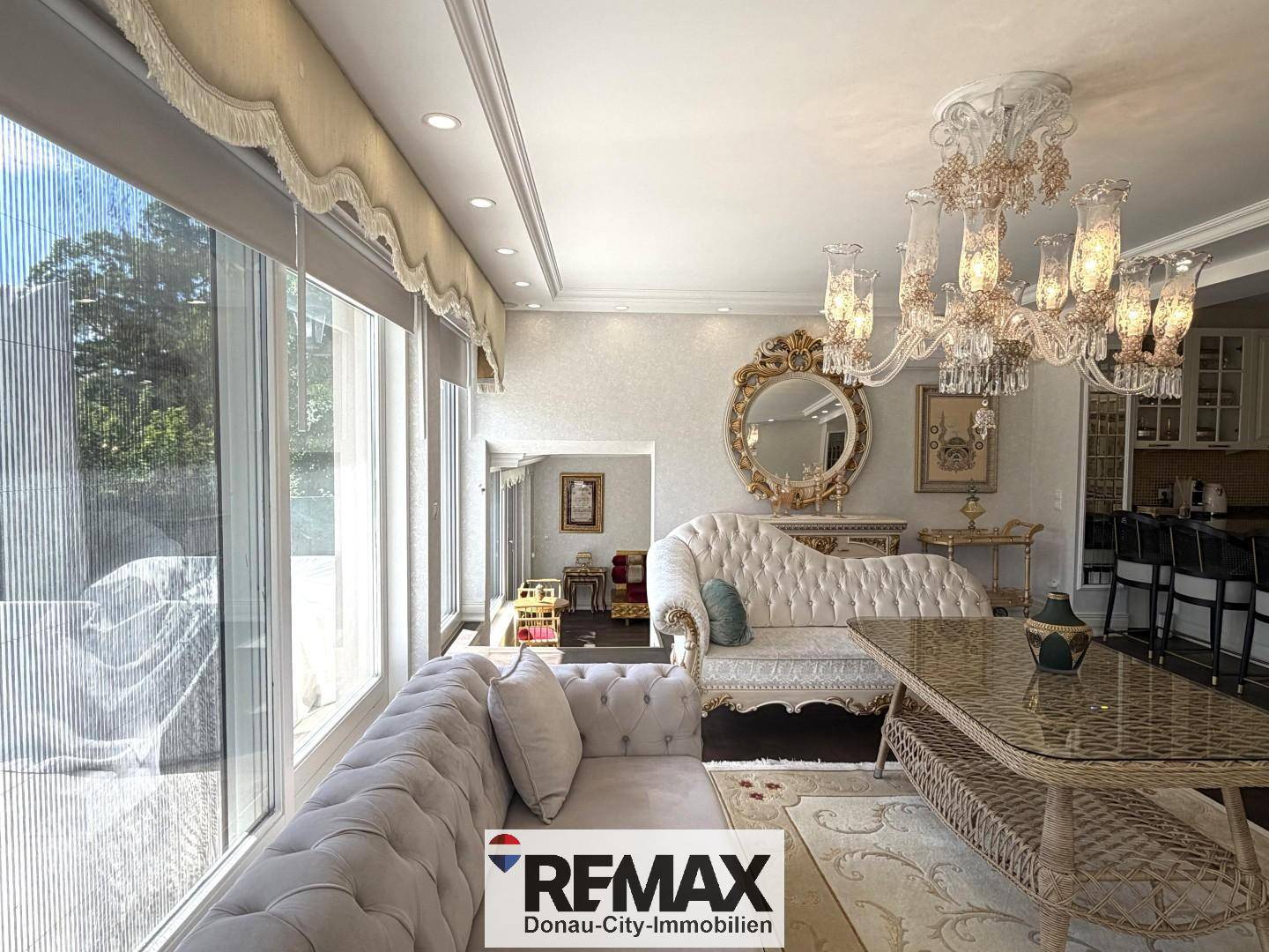 Geräumiges Wohnzimmer mit opulenten Möbeln, großen Fenstern und Zugang zur Terrasse.