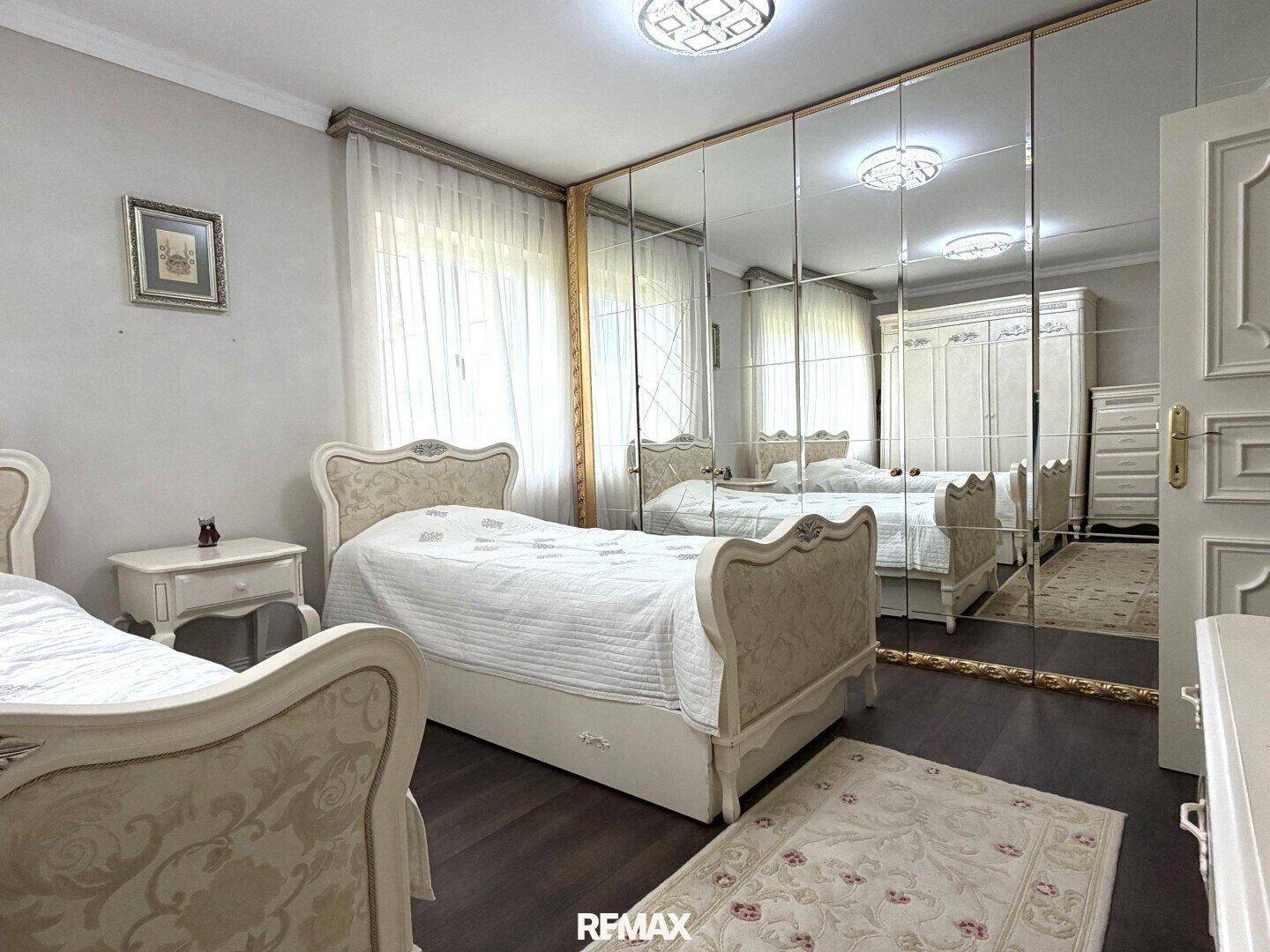 Schlafzimmer mit zwei Betten, Spiegelschränken und klassischer Einrichtung.