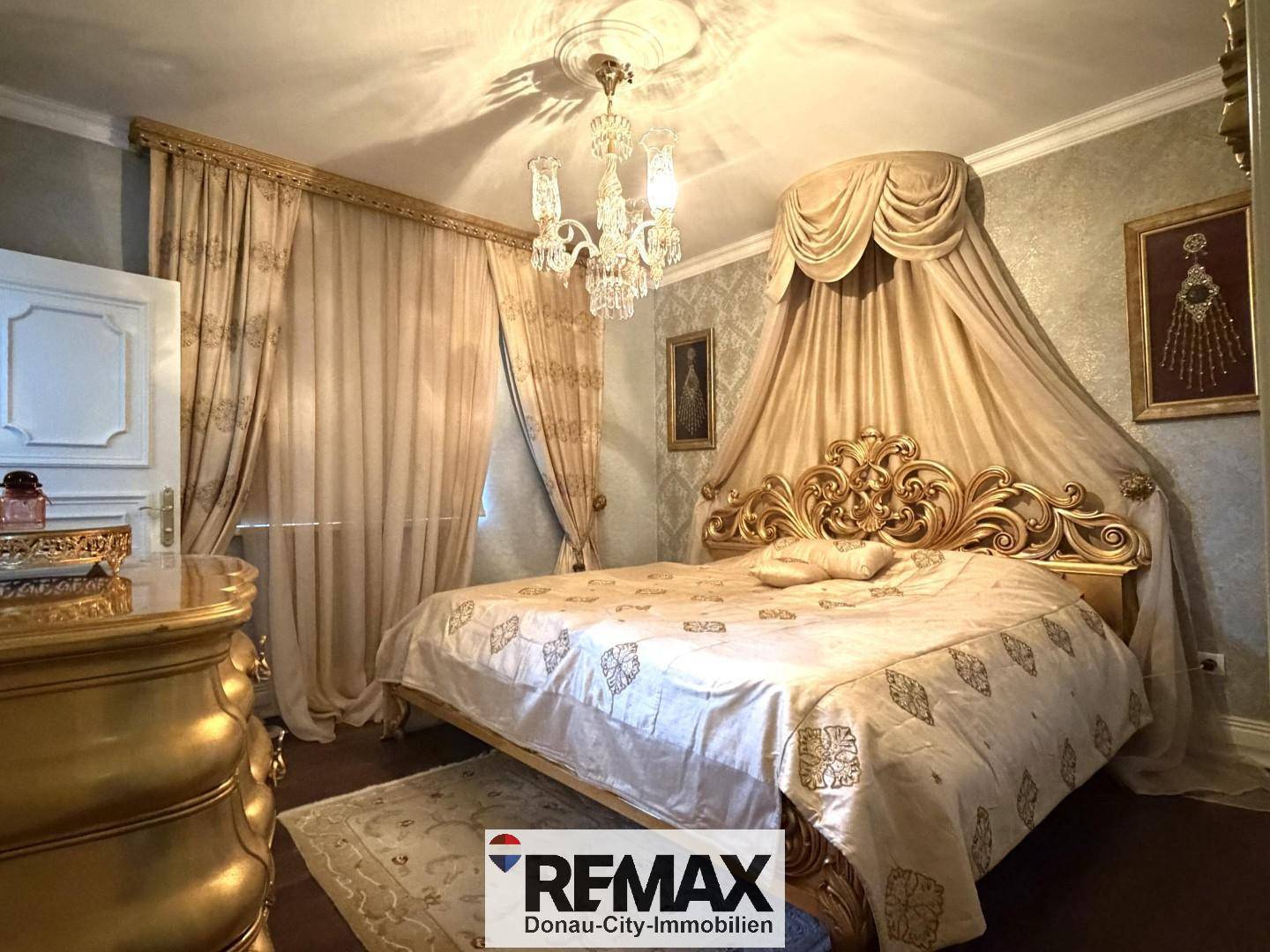 Luxuriöses Schlafzimmer mit Himmelbett, goldenen Akzenten und eleganten Vorhängen.