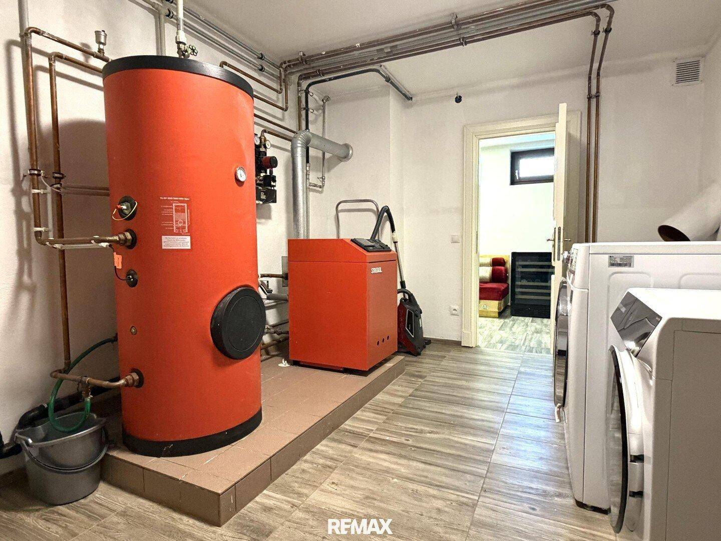 Hauswirtschaftsraum mit Warmwasserspeicher, Heizungsanlage und Waschmaschinen.
