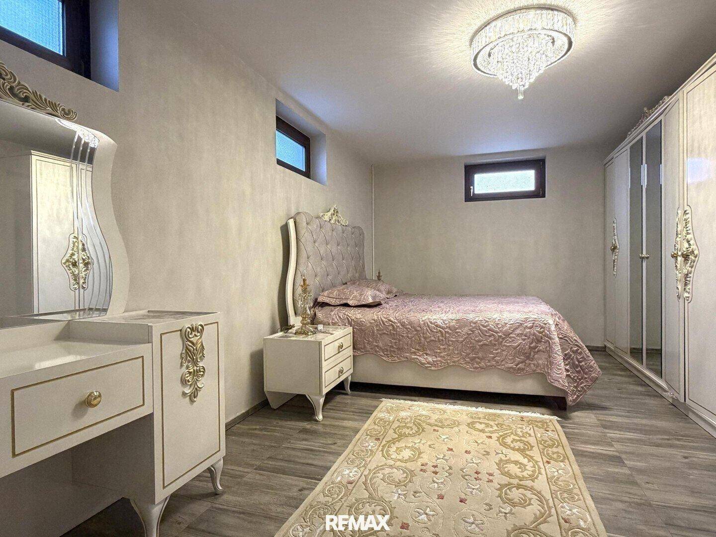 Schlafzimmer im Untergeschoss mit kleinem Fenster, Doppelbett und weißem Kleiderschrank.