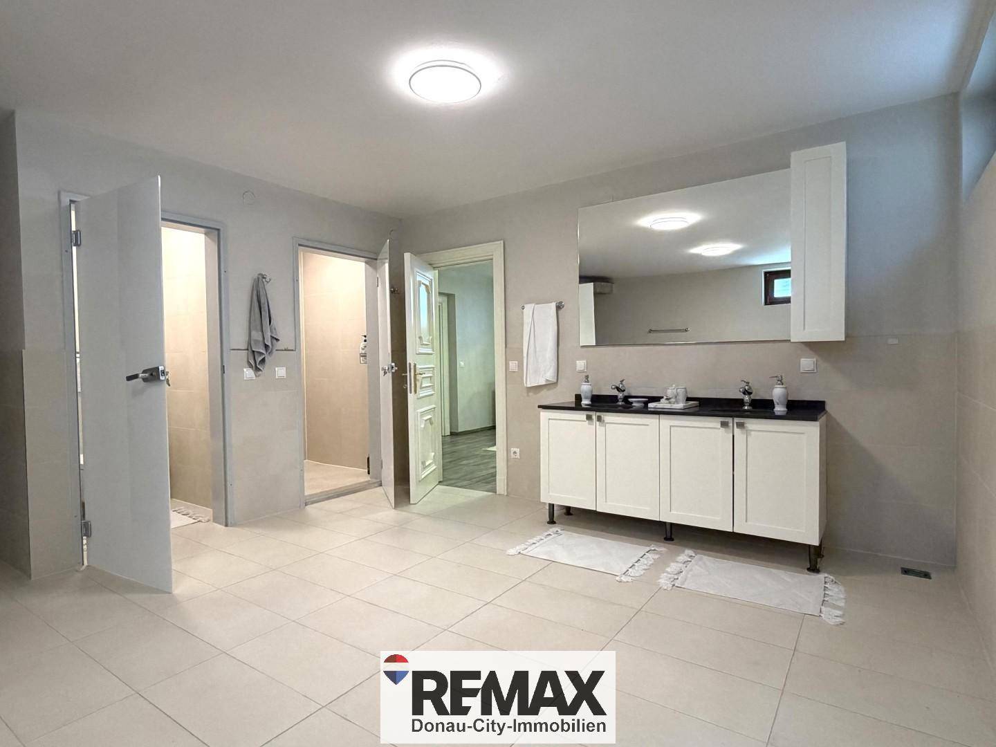 Großes Badezimmer mit Doppelwaschbecken, Spiegelschrank und begehbarer Dusche.