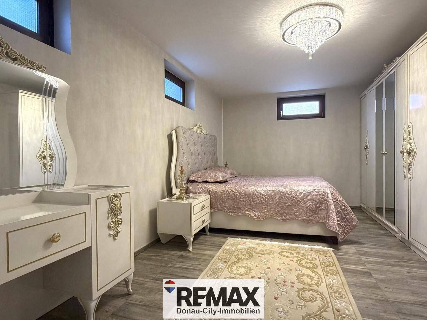 Helles Schlafzimmer im Untergeschoss mit Doppelbett, Kleiderschrank und kleinen Fenstern.