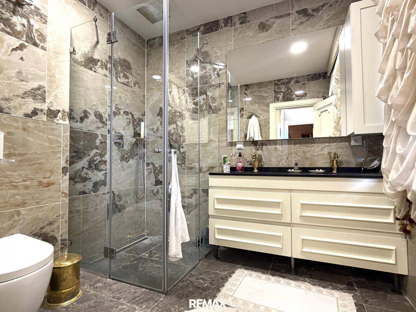 Elegantes Badezimmer mit doppelter Dusche, Doppelwaschbecken und Marmorfliesen.