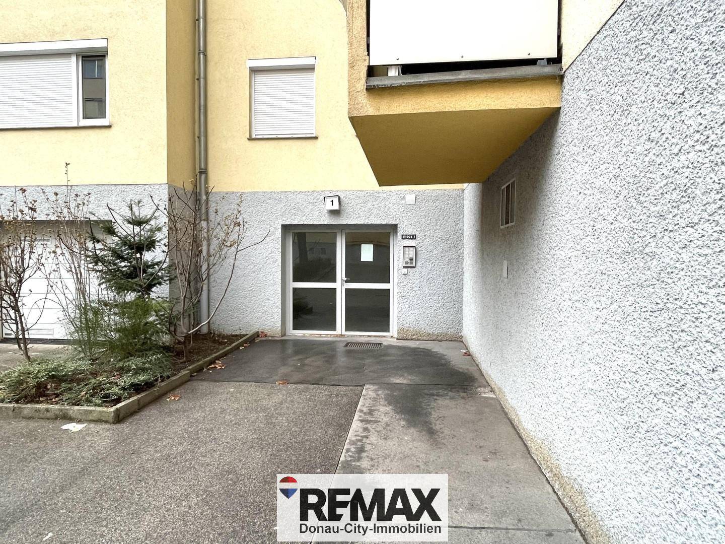 Eingangsbereich eines Wohngebäudes mit moderner Fassade und einladender Zugangstür.