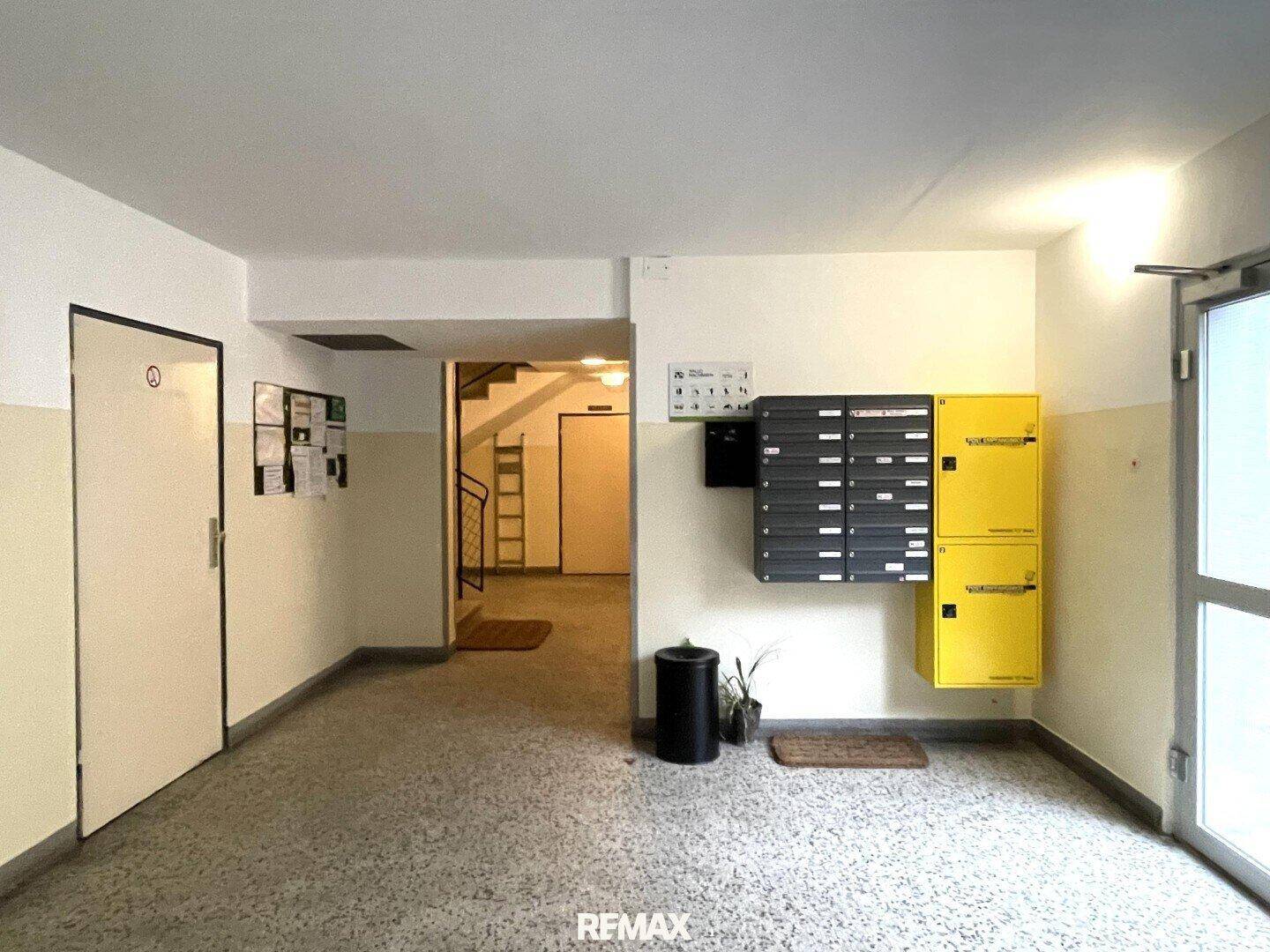Eingangsbereich eines Mehrfamilienhauses mit Briefkästen und Zugang zum Treppenhaus, funktional gestaltet.