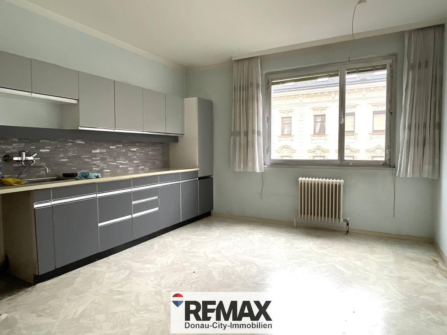 Geräumige Küche mit modernen grauen Einbauschränken, Fliesenboden und großem Fenster.