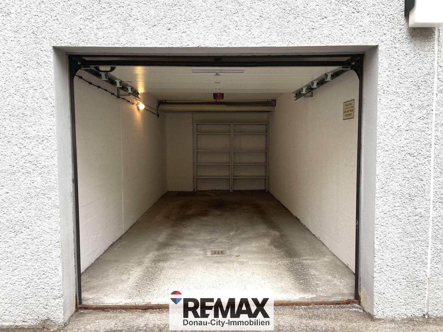 Geräumige Einzelgarage mit offenem Tor und Regalen für zusätzlichen Stauraum.