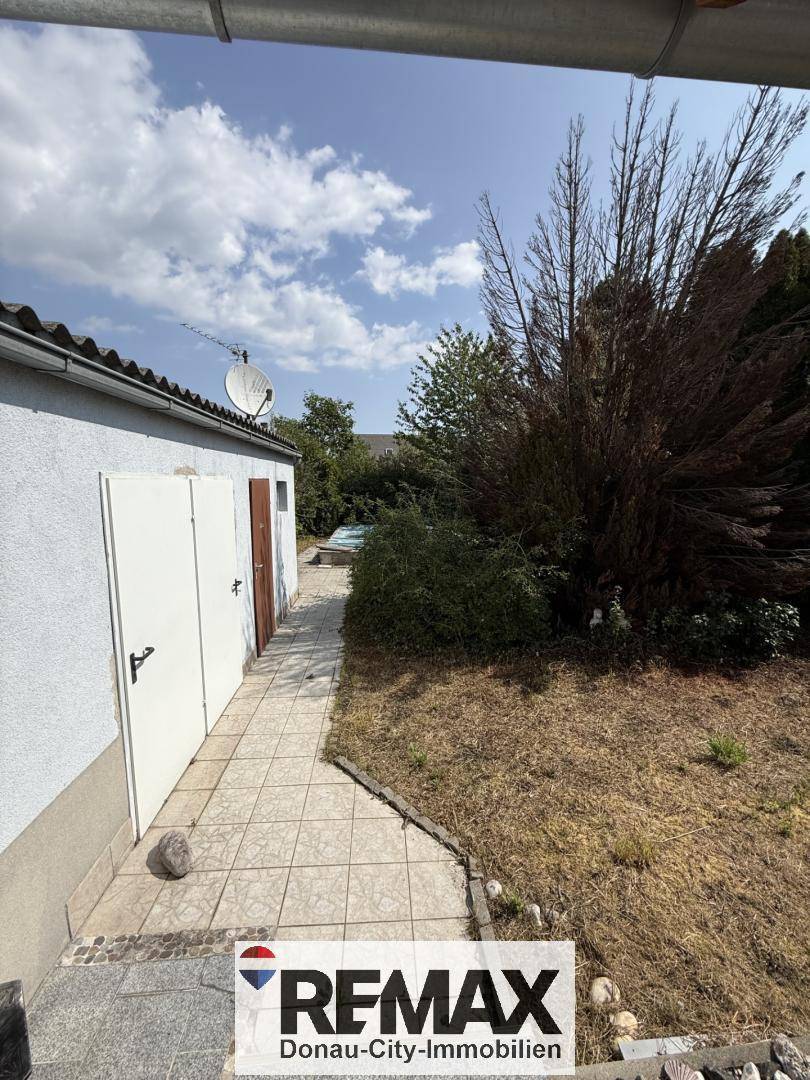 Seitenansicht des Hauses mit Abstellräumen und einem pflegeleichten Gartenbereich.