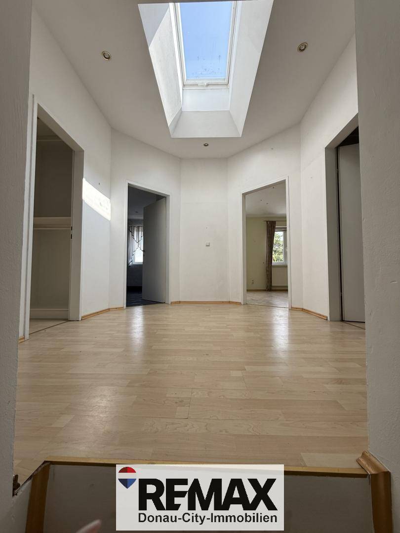 Heller Flur im Obergeschoss mit Holzfußboden und einem großen Dachfenster für viel Tageslicht.