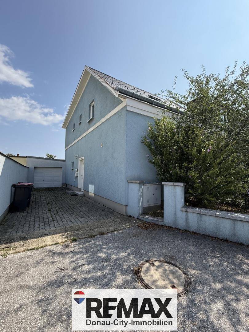 Ansicht des Hauses von der Seite mit Einfahrt, Garage und einem kleinen Vorgartenbereich.