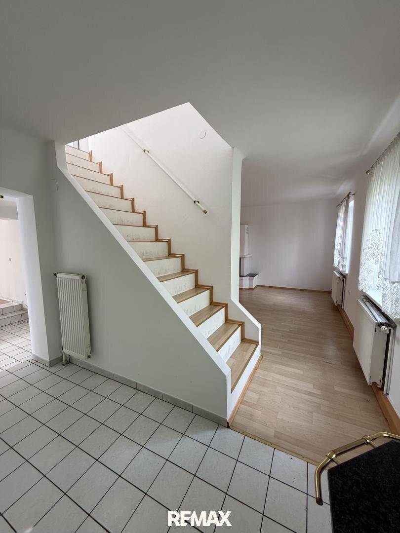 Heller Eingangsbereich mit Treppe, Fliesenboden und Zugang zu weiteren Räumen.
