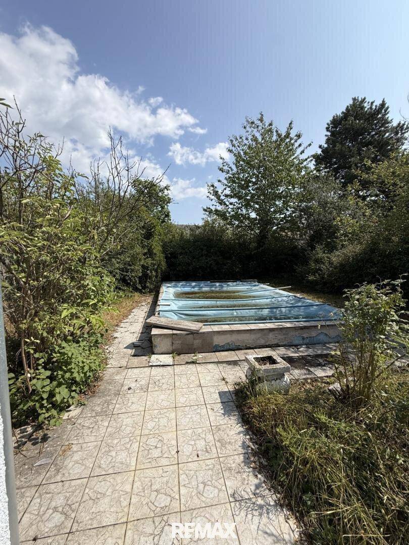 Gartenbereich mit einem abgedeckten Pool und umliegender Bepflanzung.