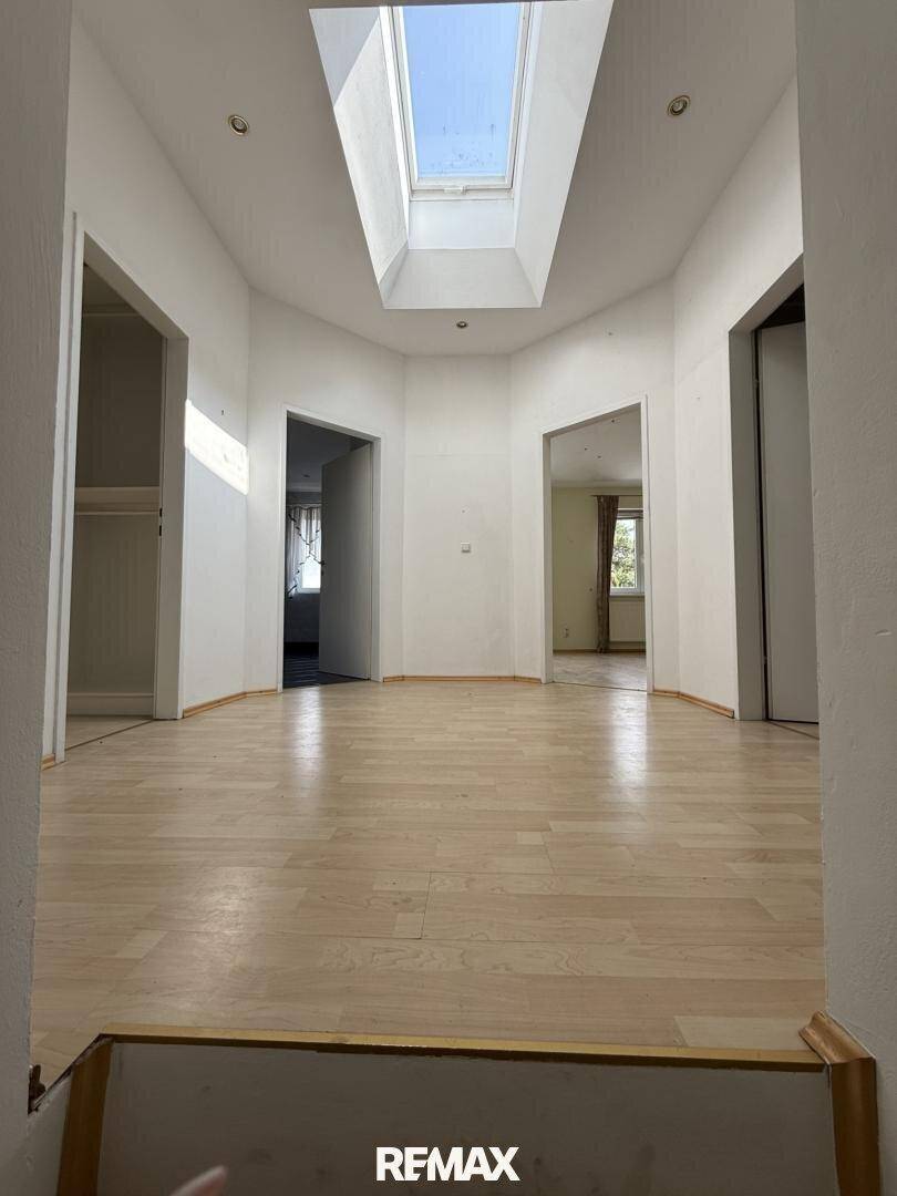 Lichtdurchfluteter Flur im Obergeschoss mit Holzfußboden und Dachfenster.