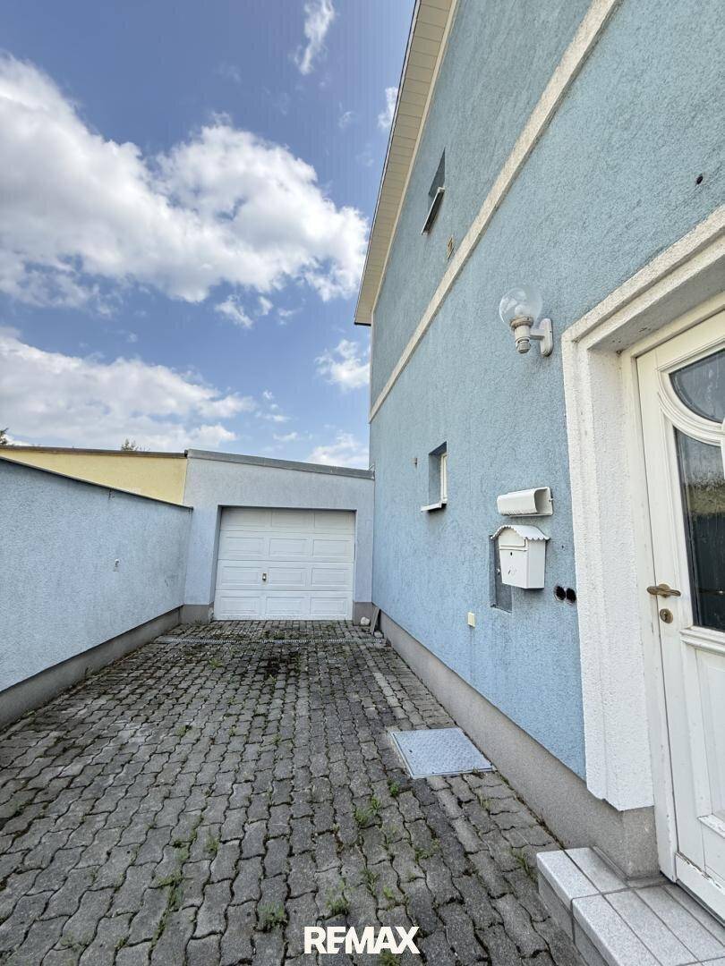 Seitenansicht des Hauses mit gepflasterter Einfahrt und Garagenzugang.