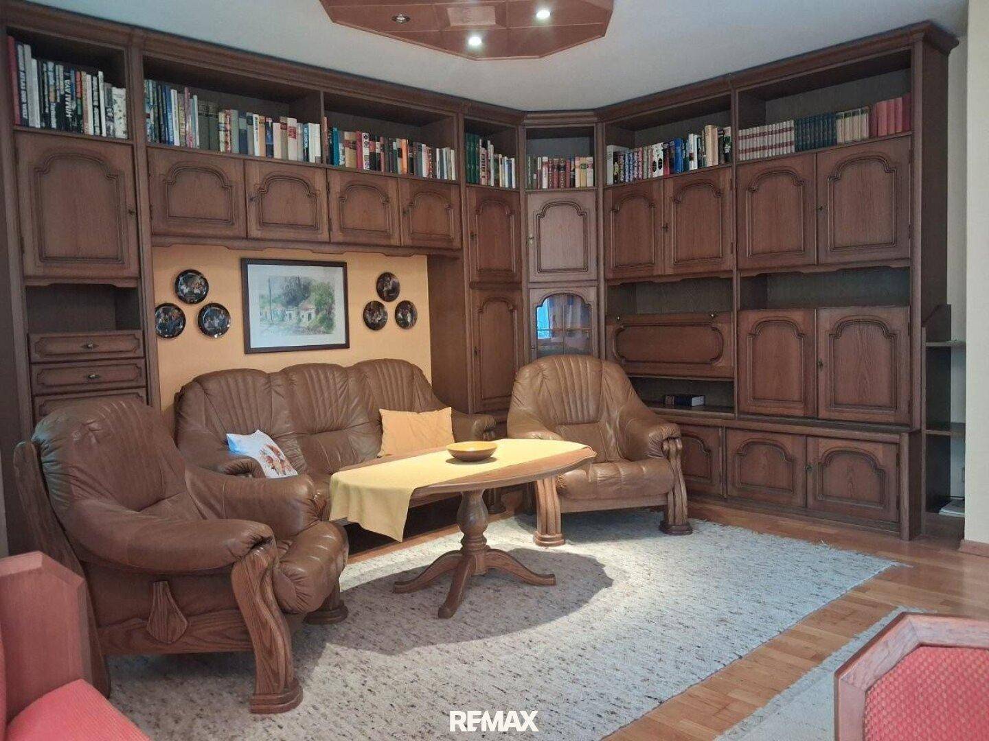 Gemütliches Wohnzimmer mit großer Bücherwand aus Holz und bequemen Ledersofas.