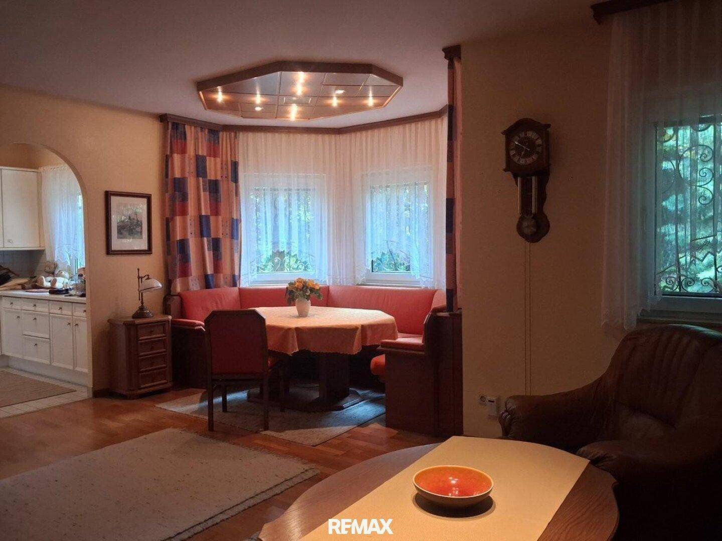 Wohn- und Essbereich mit Eckbank, Holztisch und Blick auf die Küche.