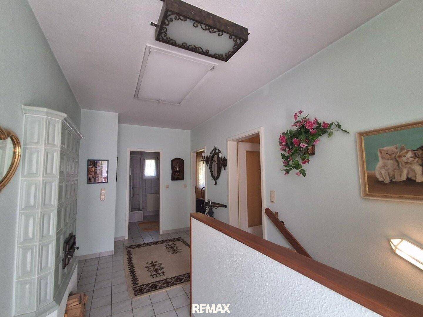 Heller Flur mit Kachelofen, Fliesenboden und Zugang zu weiteren Räumen.