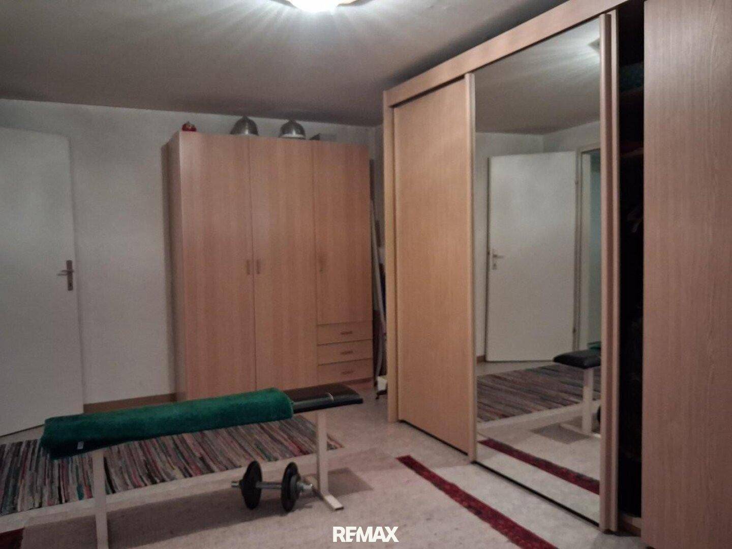 Schlafzimmer mit Spiegelschränken, Holzschränken und Fitnessgeräten.