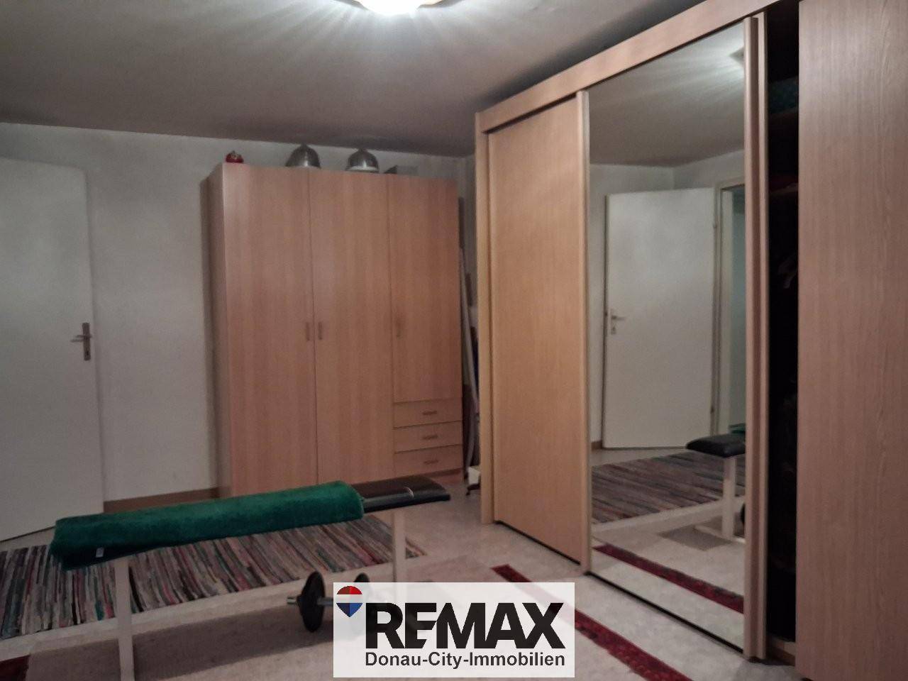 Schlafzimmer mit Spiegelschränken und Trainingsbank.
