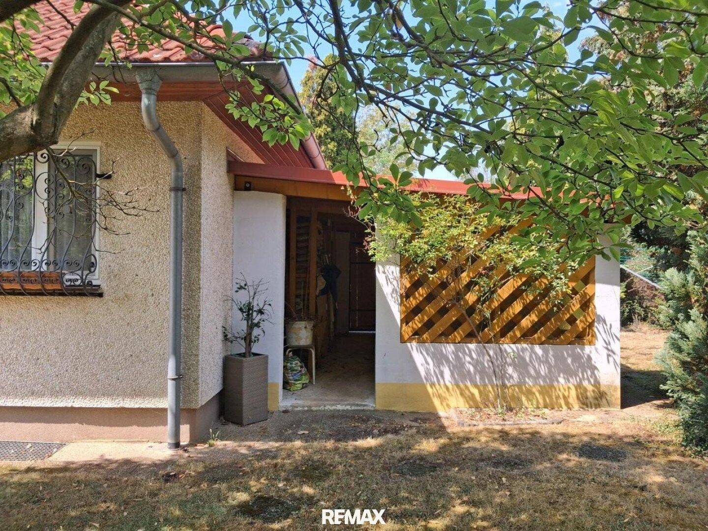 Seitenansicht des Hauses mit überdachtem Eingangsbereich oder Carport.
