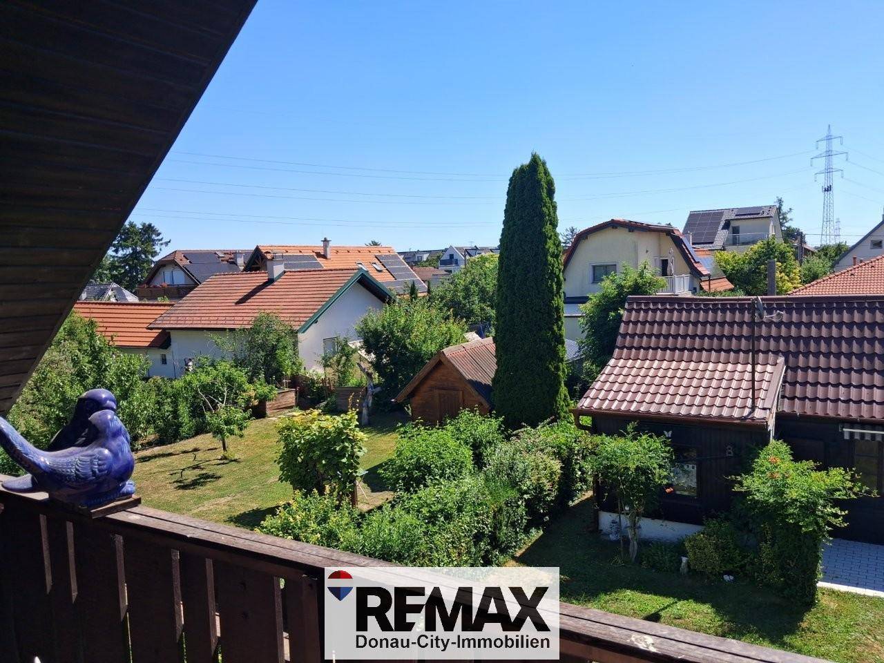 Balkon mit Holzbalkonbrüstung und weitem Blick über den Garten und die Nachbarschaft.