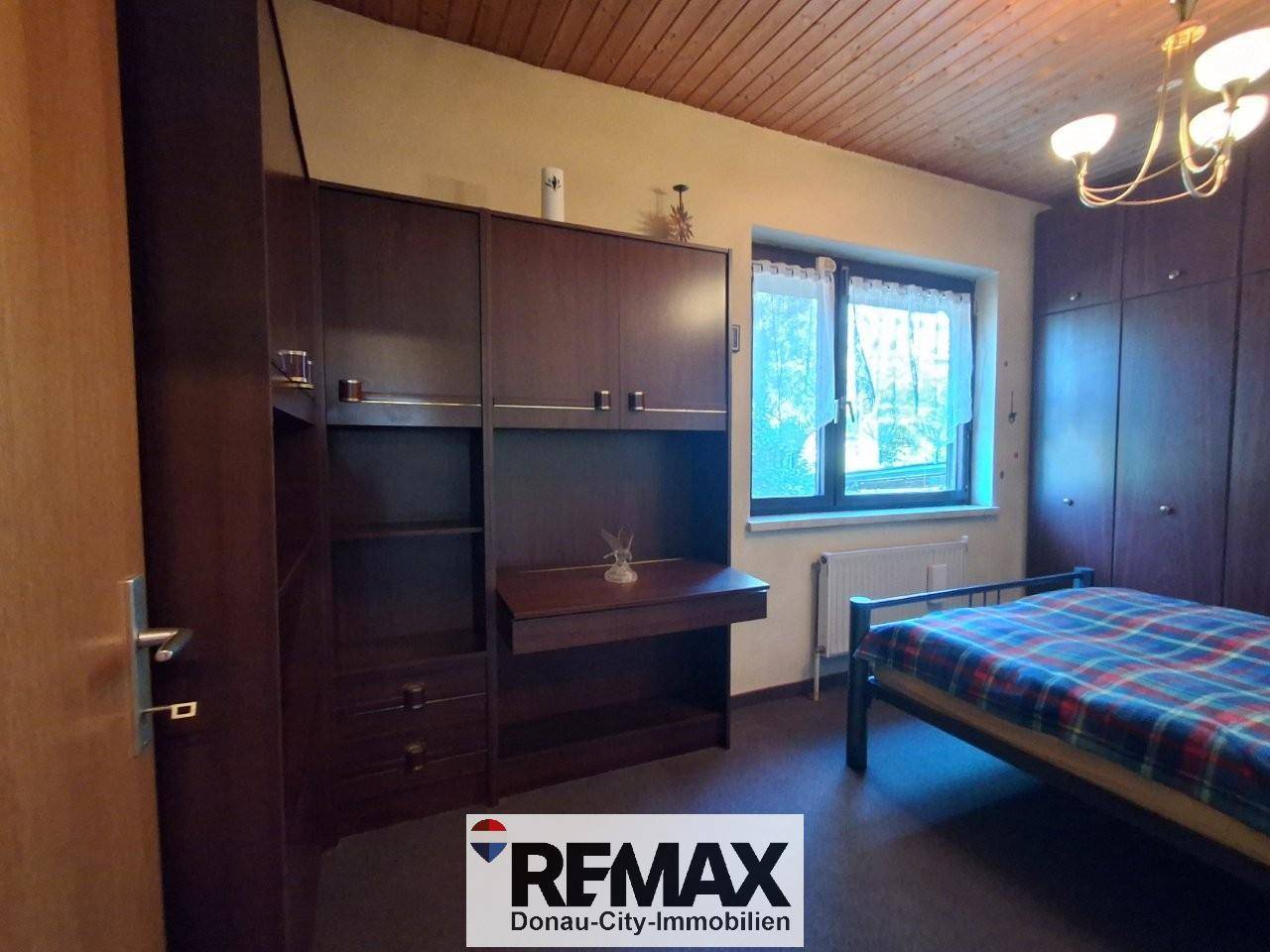 Schlafzimmer mit großem Kleiderschrank, Doppelbett und Holzdecke.