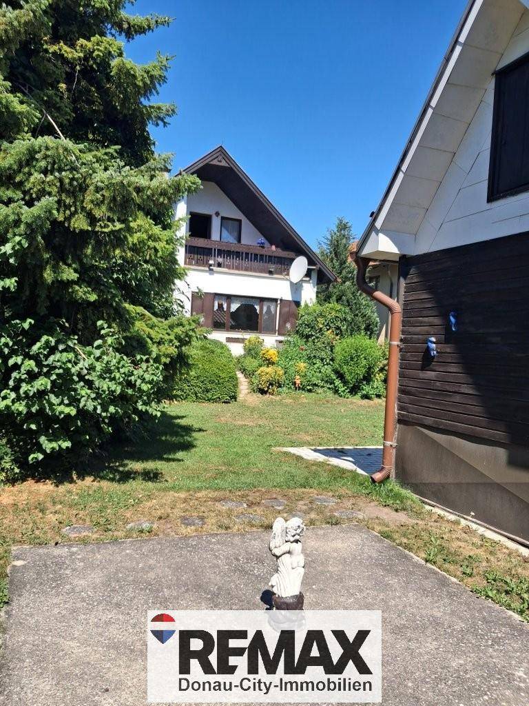 Gartenbereich mit Rasenfläche und Blick auf das Haus und die Umgebung.
