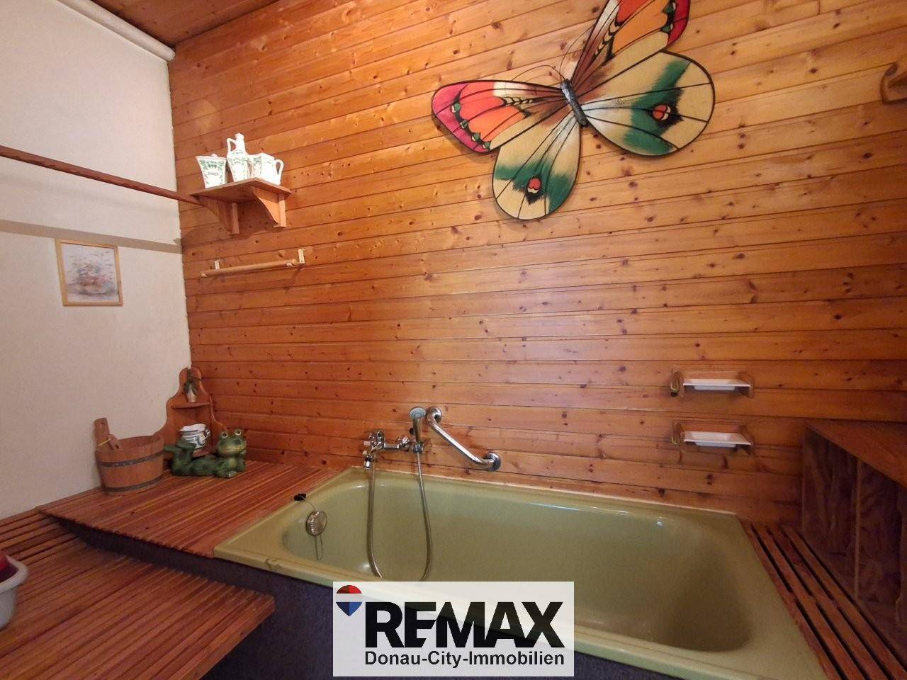 Badezimmer mit Badewanne, Holzvertäfelung und rustikalen Dekorationen.