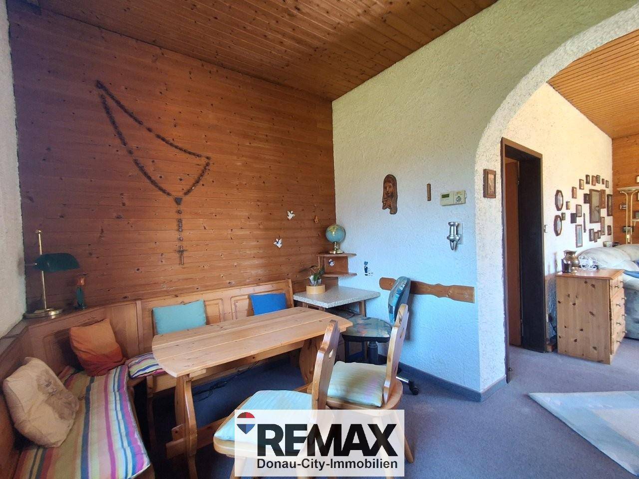 Rustikaler Essbereich mit Holztisch, Eckbank und Holzvertäfelung an der Wand.